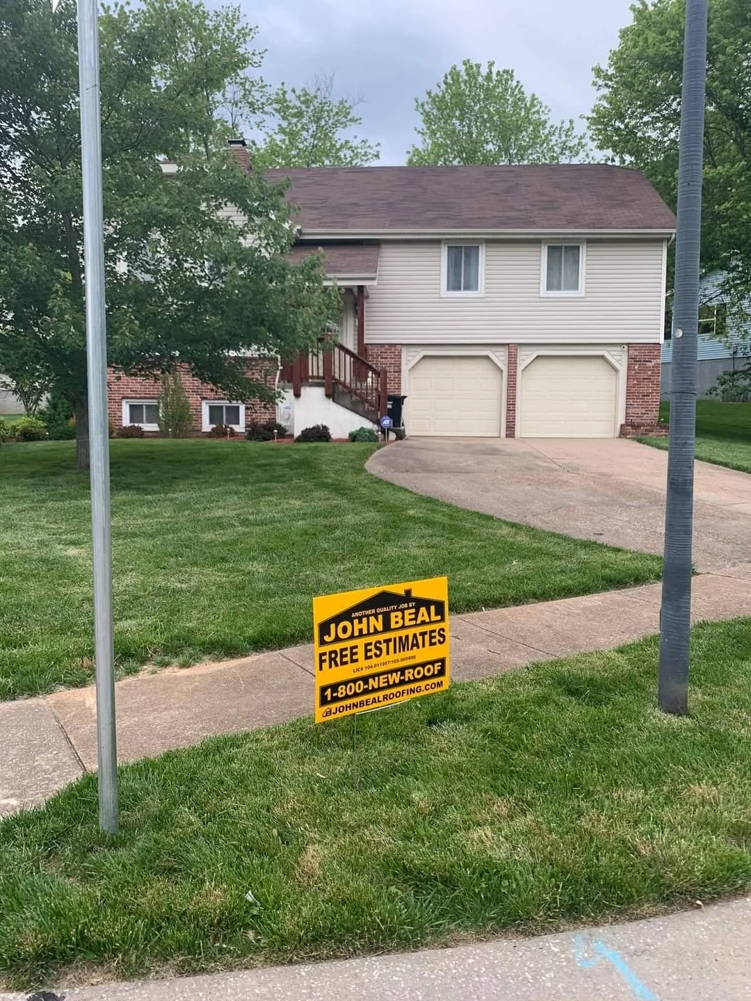 Two-story home with a new roof and a John Beal Roofing yard sign in the yard