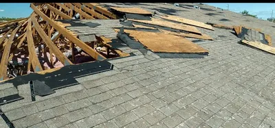 Roof damage with broken trusses and exposed underlayment — John Beal Roofing